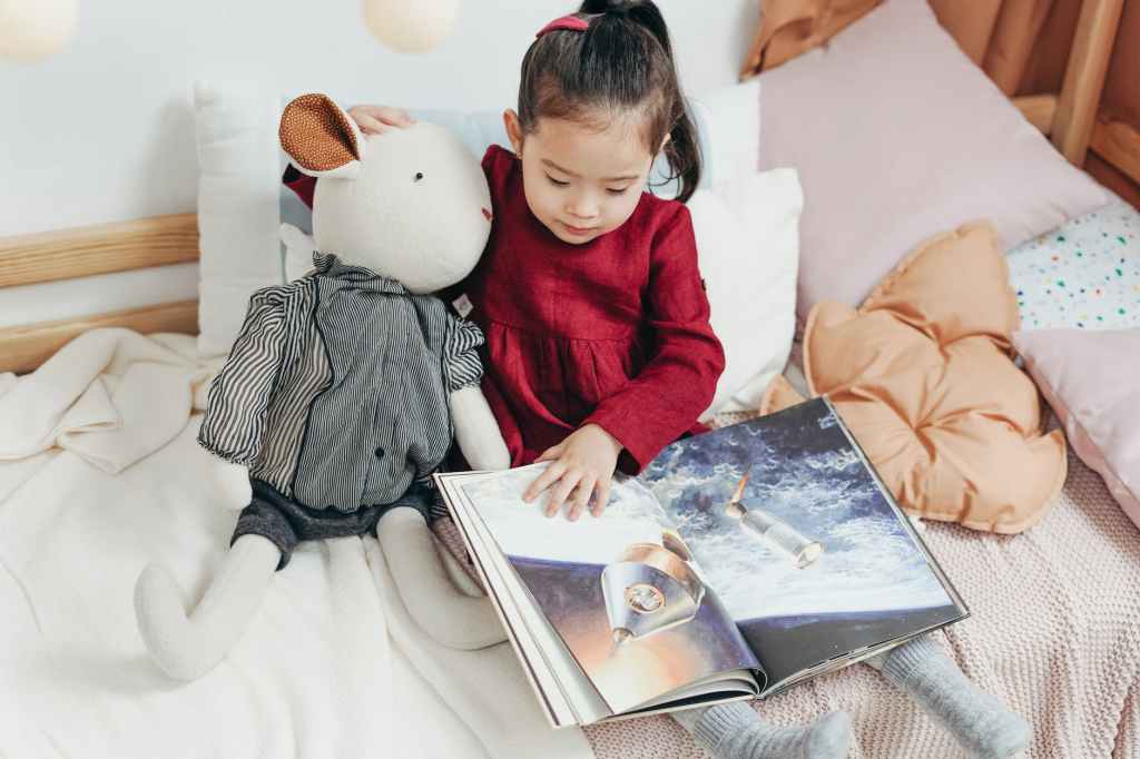 girl in red dress sitting on bed reading book