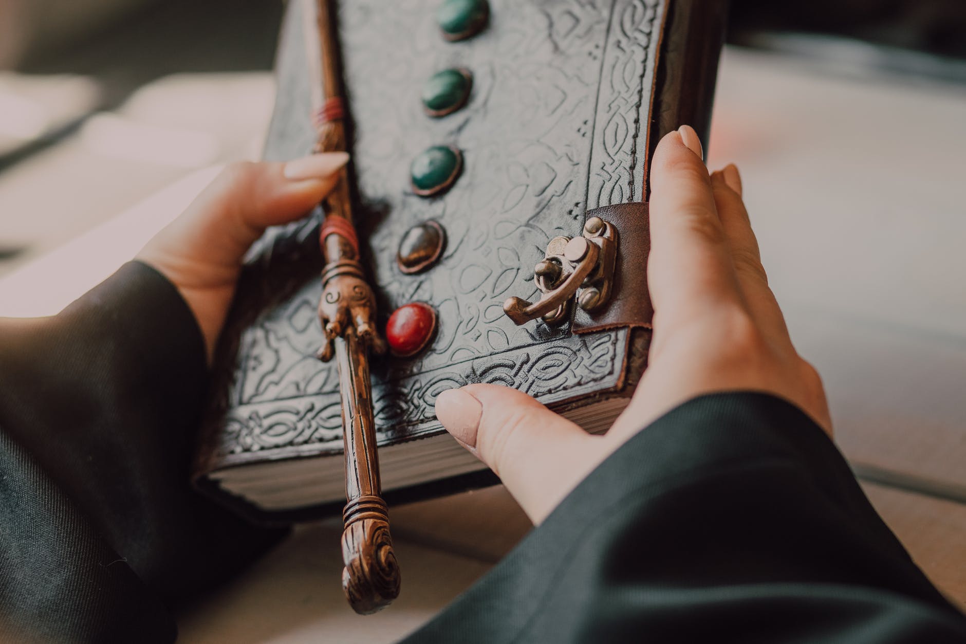 hands with medieval leather book and wand; fantasy books; author on writers week