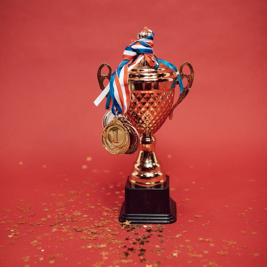 gold and blue trophy on red surface; author spotlight winning book awards