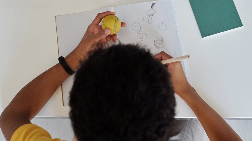 top view photo of boy drawing on white paper