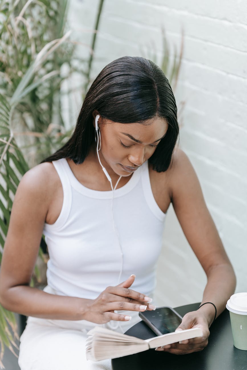 a woman using a smartphone while wearing earphones; on social media as a young or new author