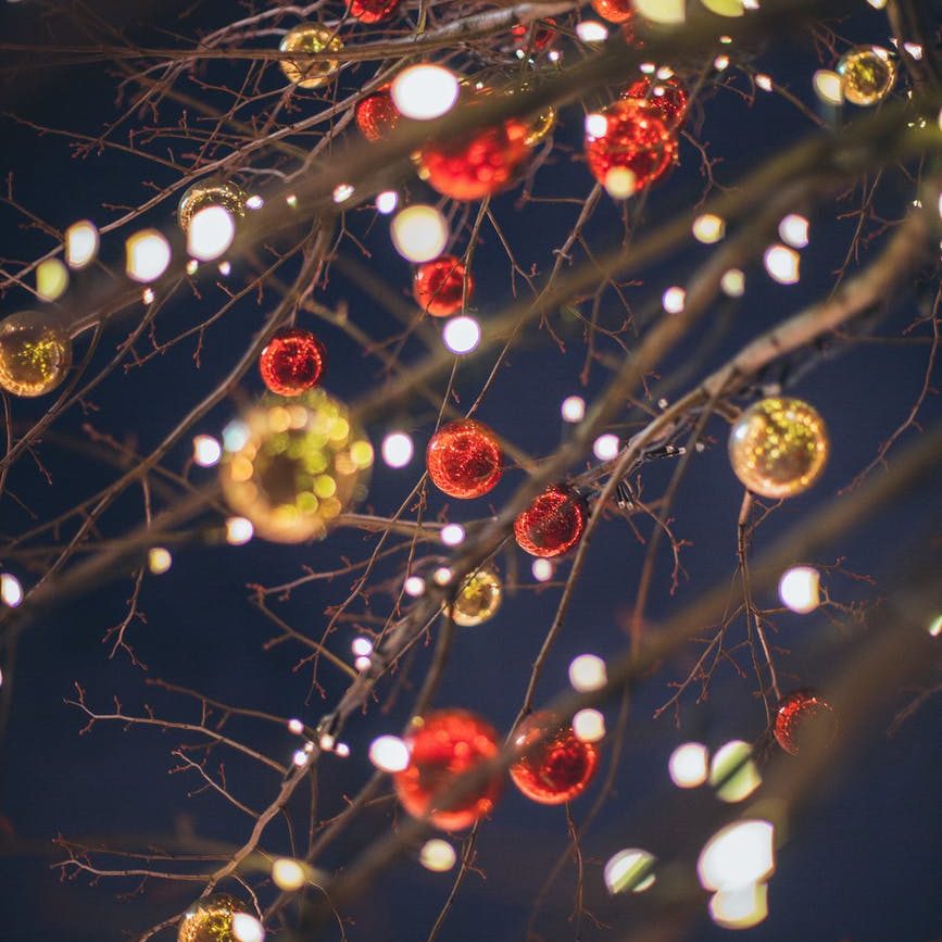 bare tree with glossy christmas toys and lights against dark sky
