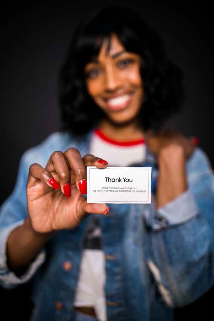 smiling woman holding a thank you card