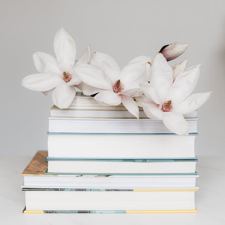 stack of books with magnolia flower on white table