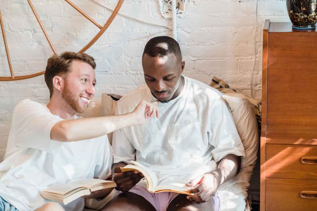 gay couple sitting in bed and reading books in the morning