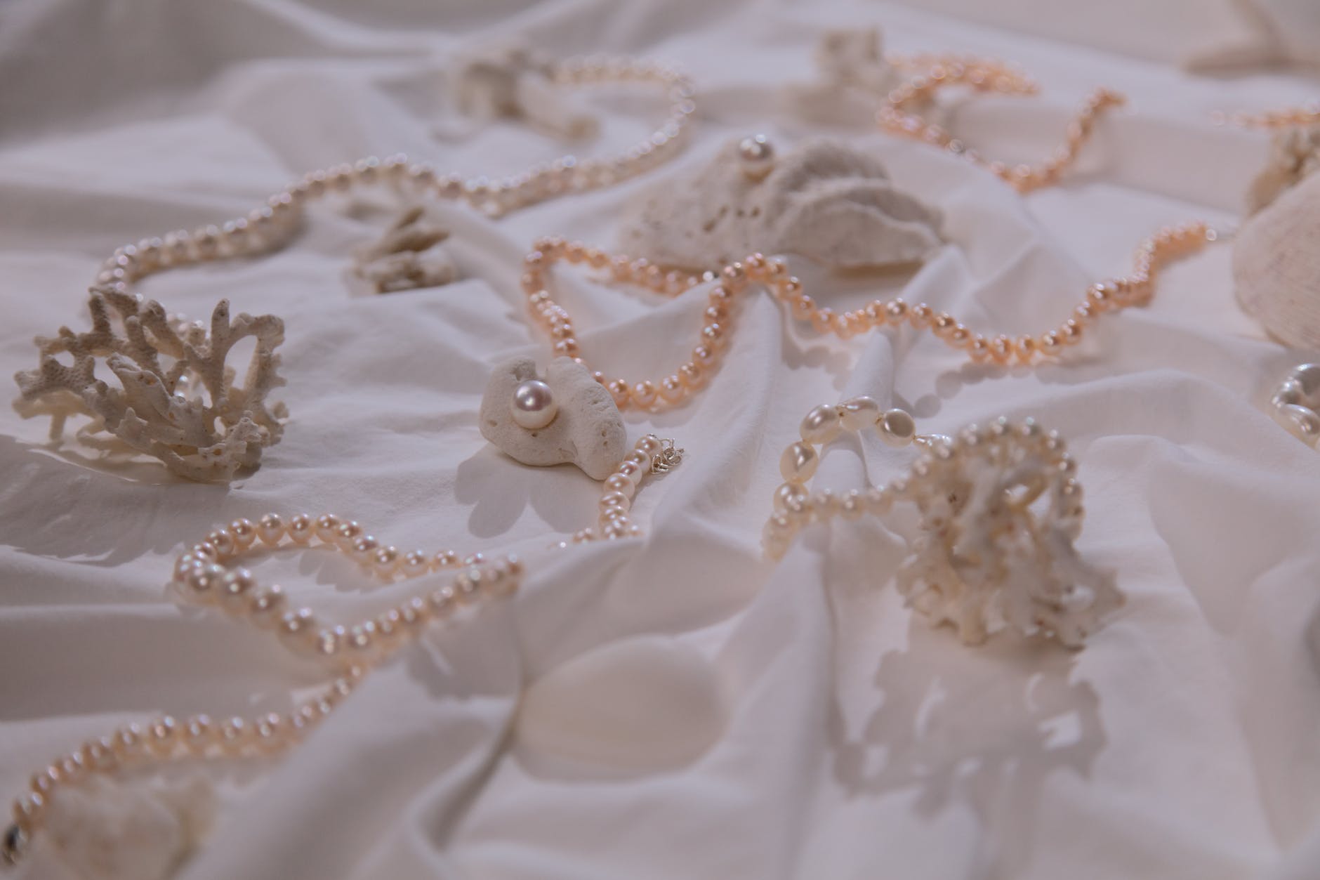 photograph of pearl necklaces on a white cloth