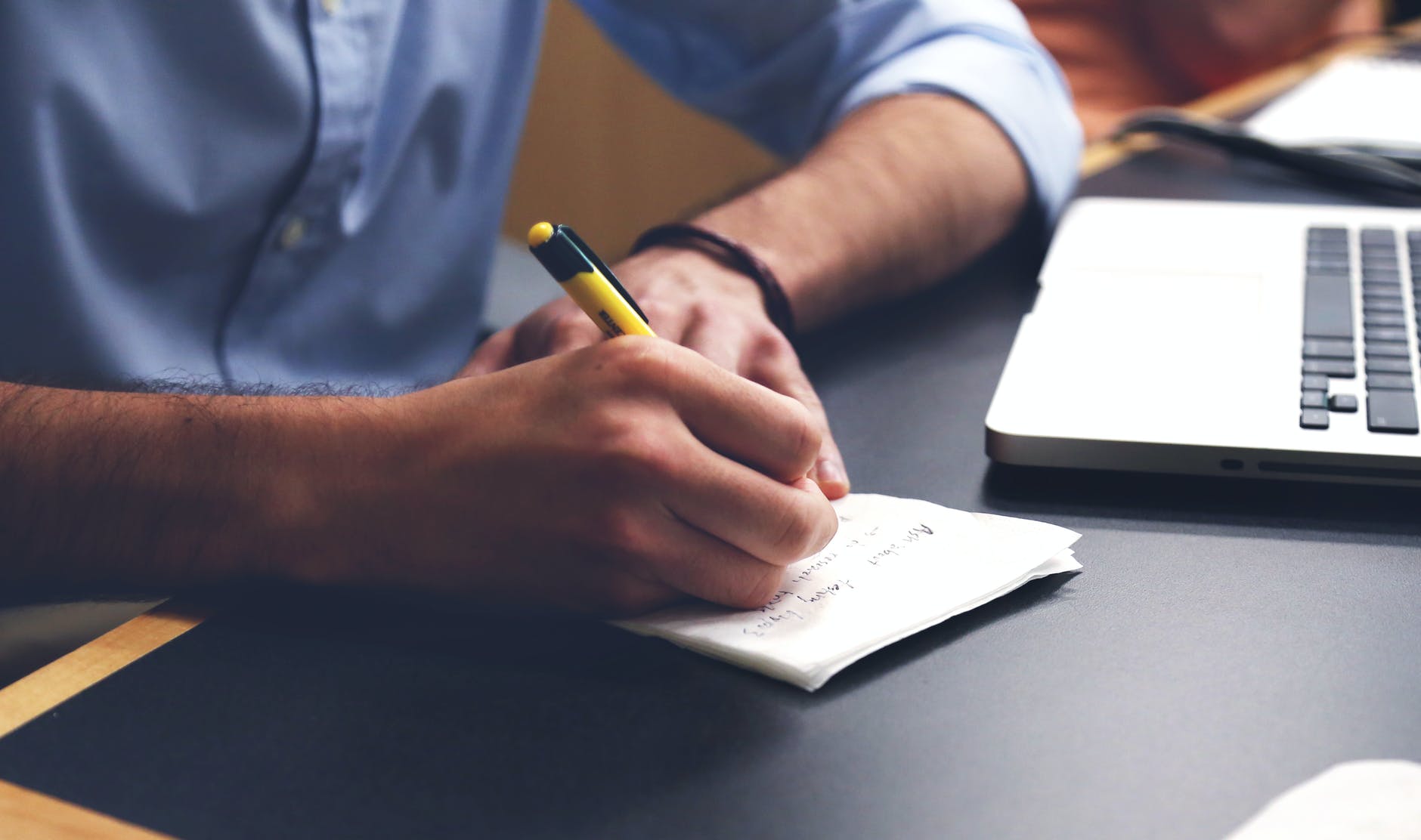 person writing on paper using yellow and black pen; Keep your notes; world building