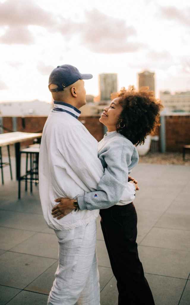 man wearing white jacket and woman wearing blue jacket hugging
