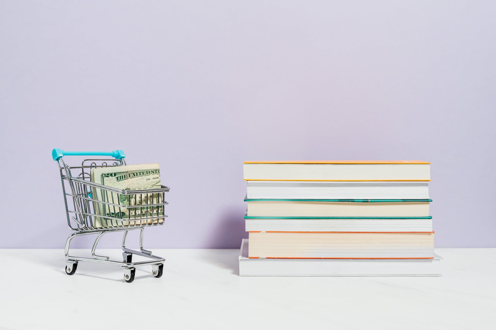 stack of books beside a shopping cart with cash money; price for book editing