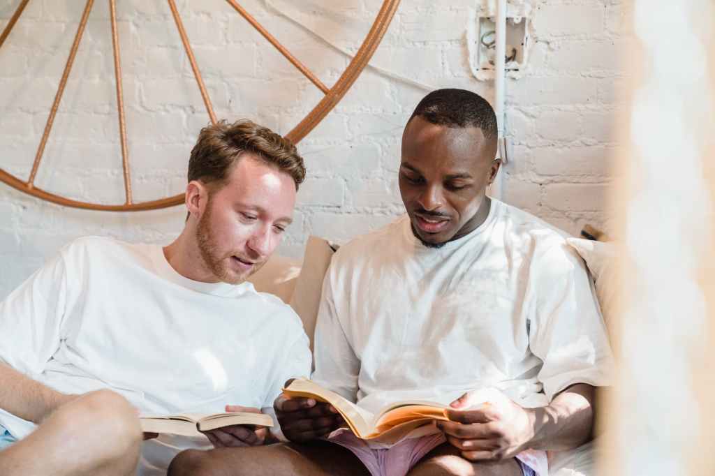 gay couple sitting in bed and reading books in the morning