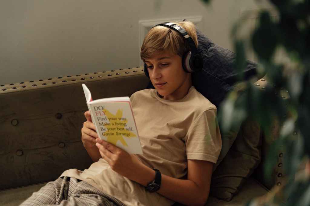 a boy reading a book while listening to music