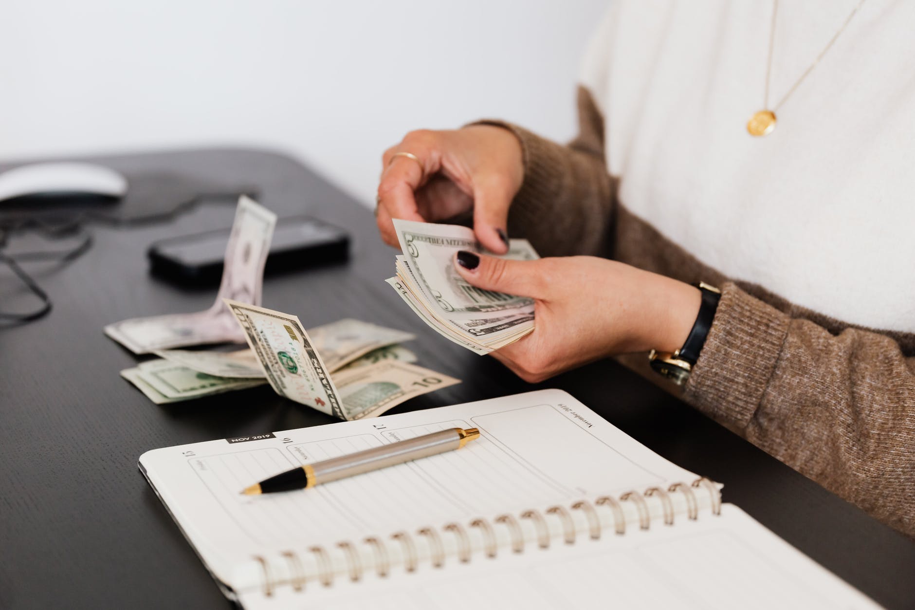 crop payroll clerk counting money while sitting at table; photo from Win's Books Author Spotlight guidelines 