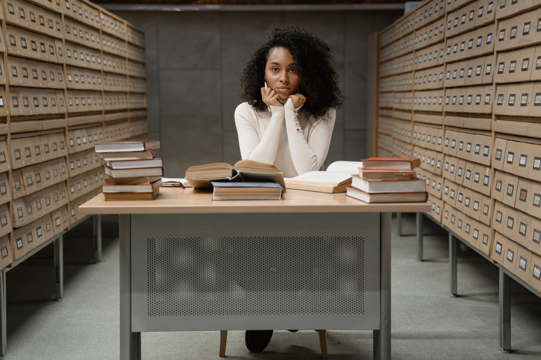 a woman with curly hair sitting on a table with stacks of books