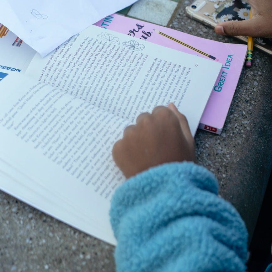 crop ethnic child doing homework on table