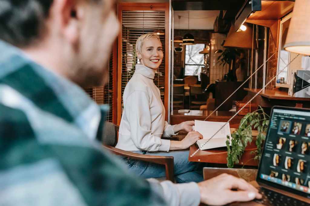 cheerful woman looking at man working on laptop in cafe; book editors