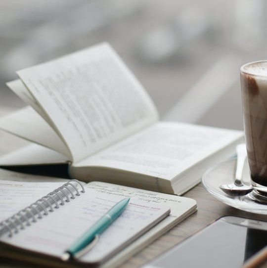 warm coffee drink with open book and writing pad