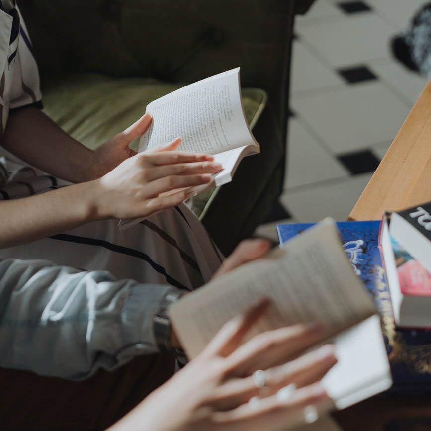 person in gray jacket holding white paper; book club of young people