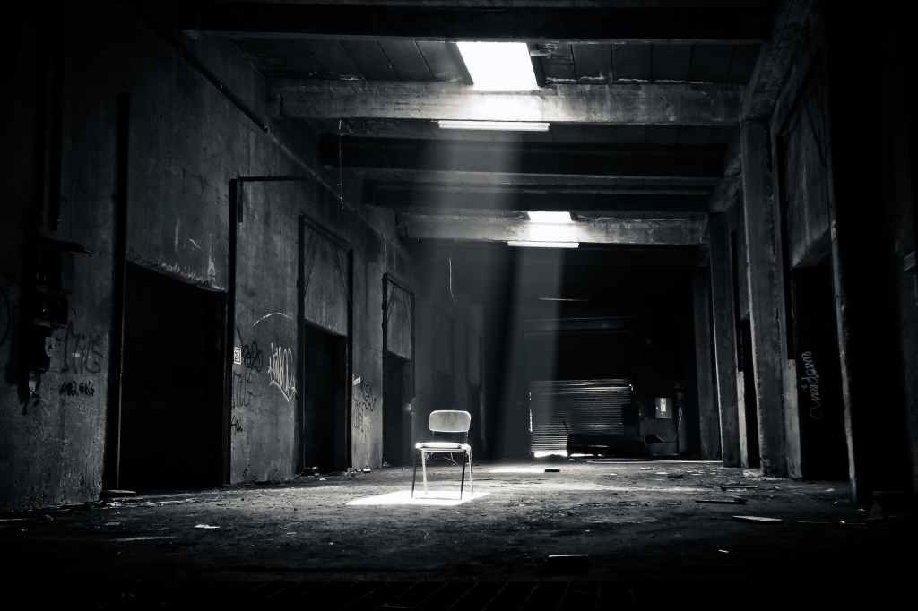 grayscale photo of chair inside the establishment; difference between paranormal and horror