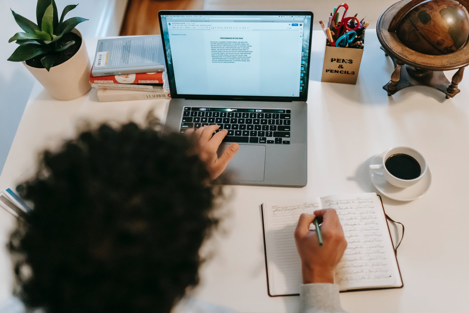 unrecognizable author typing on laptop near coffee at home author writing in their book; photo from Win's Books Author Spotlight guidelines 