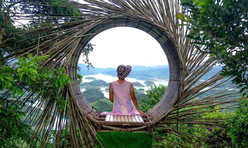back view of a woman wearing a summer hat sitting on a wicker construction